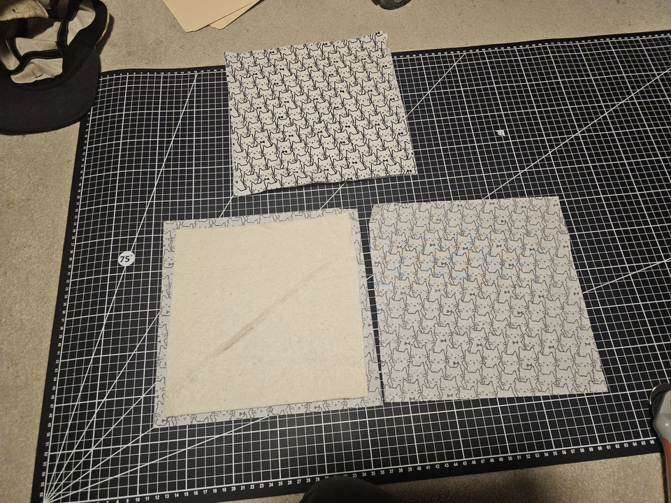 cat fabric and batting in squares lined up on a cutting mat