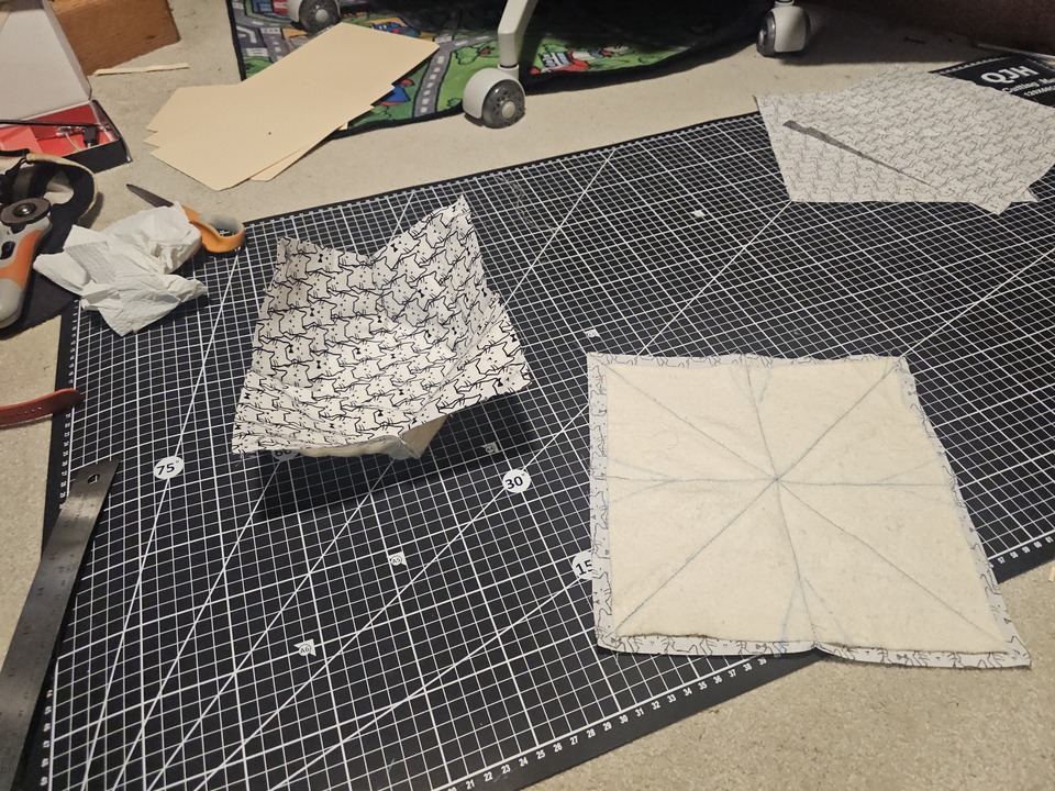 one inverted bowl cozy half - with the darts cut off. next to the remaining half of flat sewed together fabric